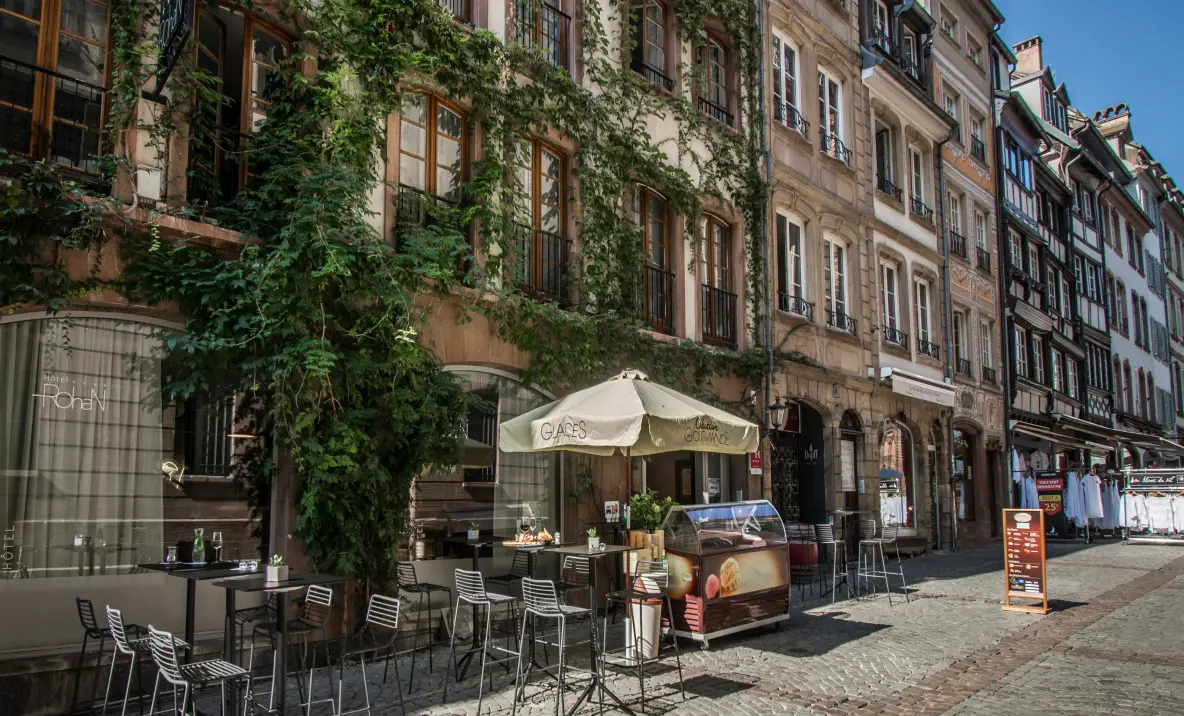 Terrasse extérieure de l’Hôtel Rohan Strasbourg avec tables, chaises et façade végétalisée