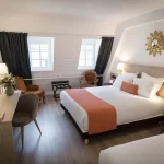 Bright triple room with double bed and seating area at Hotel Rohan in Strasbourg city centre