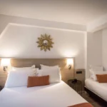 Chambre triple de l’Hôtel Rohan Strasbourg avec lit double, lit simple et décoration murale lumineuse