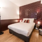 Small double room at Hôtel Rohan Strasbourg with double bed and textured burgundy feature wall