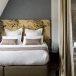 Suite de l’Hôtel Rohan Strasbourg avec lit double, tête de lit florale et espace salle de bain attenante