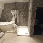 Salle de bain de suite à l’Hôtel Rohan à Strasbourg avec baignoire îlot et douche à l’italienne